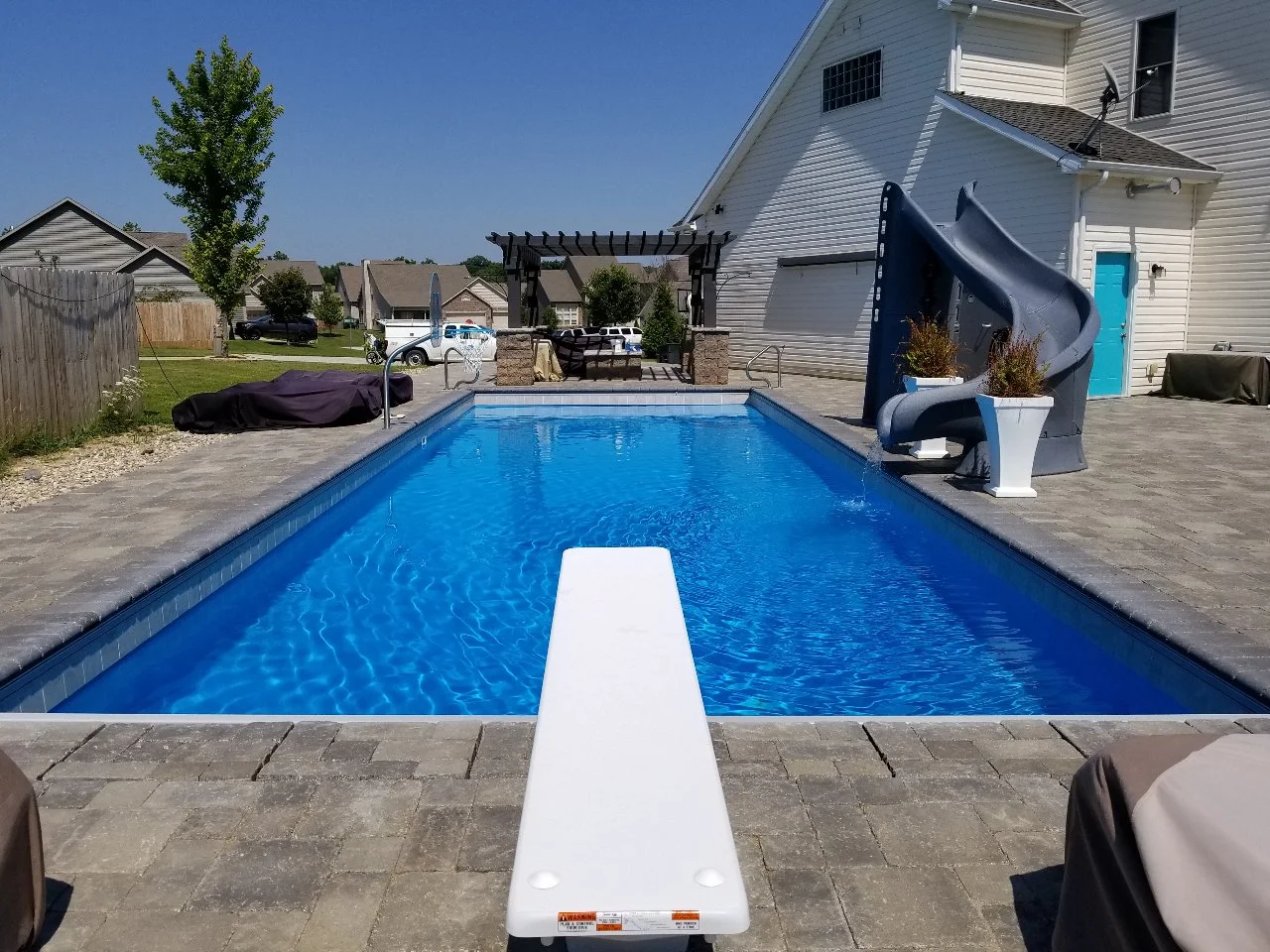 A finished fiberglass pool with paver decking and a basketball hoop from the company project gallery