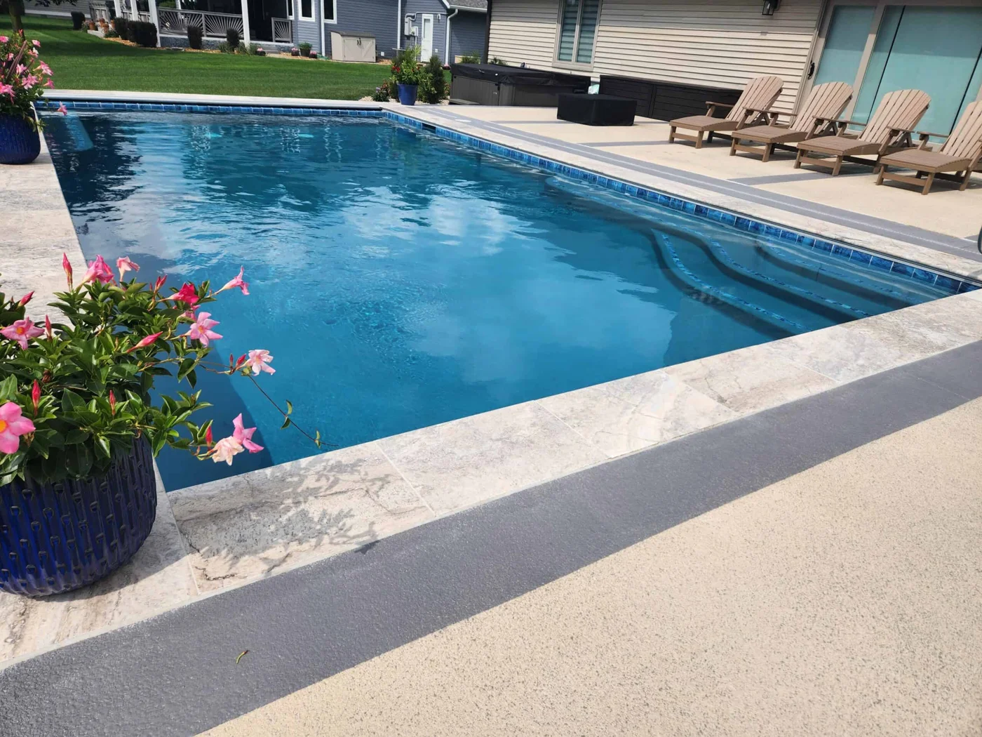 Rectangular pool with patterned waterline tile, broad stone coping and a seating patio