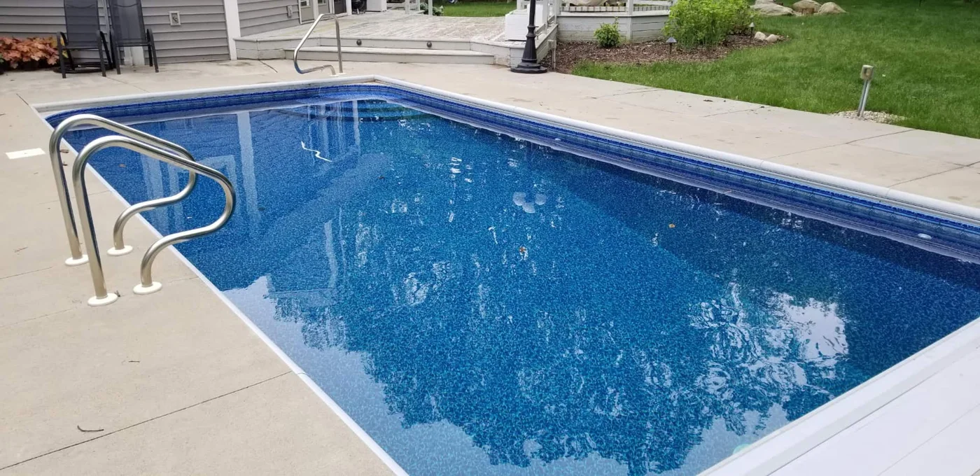 Vinyl liner pool with a blue patterned liner, entry steps, handrails and concrete deck